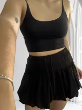 Minifalda negra con cintura elastizada y cordón ajustable.