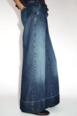Jeans de tiro bajo con pernera recta y bajo con vuelta. Cuenta con cinco bolsillos y cierre frontal con cremallera y botones.