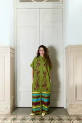 Vestido largo verde militar de popelina de algodón, con diseño oversized, cuello mao, mangas cortas, bolsillos laterales y cierre frontal con botones. Presenta un estampado de flores grandes en la parte superior y franjas horizontales de colores en el ruedo.