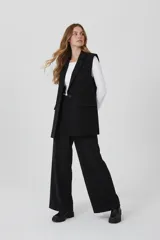 Chaleco largo de corte sastrero en color negro, con solapas clásicas, cierre frontal de un botón y bolsillos laterales con solapa.