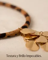 Collar con cordón de cuerina con estampado animal print y dije colgante de acero con baño de oro compuesto por múltiples piezas circulares pequeñas.