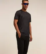 Pantalón deportivo de corte ajustado, color negro, con cintura elástica, cordón de ajuste, bolsillos laterales con cremallera, bandas laterales en contraste y cremalleras en los tobillos.