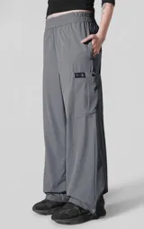 Pantalón de corte oversize confeccionado en microfibra técnica elastizada, color gris carbón. Presenta cintura elástica, bolsillos laterales, un bolsillo cargo con cierre de broche snap y sistema de elásticos con tancas en los tobillos para regular la apertura.