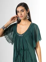 Vestido largo de seda italiana color verde oscuro, con capas escalonadas con flecos, escote en V con detalle de paillettes y mangas cortas fluidas.