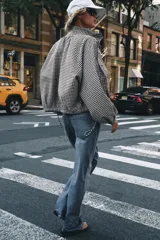 Chaqueta de manga larga con estampado de cuadros vichy en tonos marrón y blanco, cuello camisero, cierre frontal con botones y bajo ajustable con cordón.