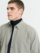 Camisa de franela lisa con cuello button-down, manga larga, botones al tono y bolsillo frontal en el pecho.