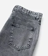 Pantalón de jean modelo baggy con bolsillos cargo laterales, cintura con trabillas y cierre frontal con botón y cremallera.