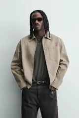 Sobrecamisa boxy fit de hombre confeccionada en tejido efecto ante color beige, con cuello solapa, manga larga con puño abotonado, bolsillo de parche en el pecho y cierre frontal con botones a presión ocultos.