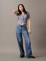 Pantalón de jean corte relaxed de pierna ancha, con diseño clásico de cinco bolsillos, cierre de botón y cremallera, en un lavado azul medio.