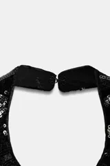 Top de cuello halter confeccionado en terciopelo con aplicación de lentejuelas brillantes que forman un patrón de rayas horizontales. Presenta espalda descubierta y cierre en el cuello.