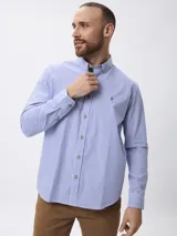 Camisa de manga larga con estampado de rayas verticales en azul y blanco, cuello abotonado y cierre frontal con botones.