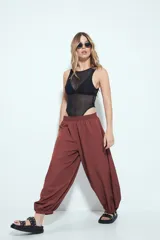 Pantalón ancho estilo Aladdin de tiro bajo, color marrón rojizo, con cintura elastizada y puños ajustados en los tobillos.