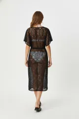 Kimono largo de encaje blanco con diseño holgado, cuello profundo y ajuste mediante cordón fino en la cintura. Presenta un patrón floral calado y mangas cortas amplias, ideal para usar como salida de baño.