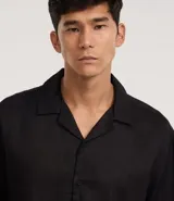 Camisa masculina blanca de lino, modelo boxy, con cuello bowling, manga corta y abotonado delantero.