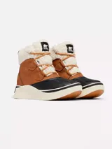 Bota de invierno impermeable Sorel modelo Out N About IV Chill, confeccionada en cuero marrón con puntera y base de goma negra, suela gruesa de goma blanca, y detalles de forro y cuello de borrego sintético blanco con cordones tostados.