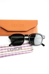 Lentes de sol polarizados con armazón negro de diseño geométrico y lentes oscuros.