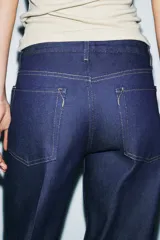 Jeans de tiro bajo color azul oscuro, corte recto, con cinco bolsillos y cierre frontal de cremallera y botón. Presenta un efecto lavado y el bajo está acabado en vuelta.