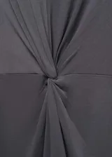 Vestido midi sin mangas de algodón, con cuello redondo y diseño recto. Presenta un detalle de nudo central que genera un efecto drapeado en la parte frontal.
