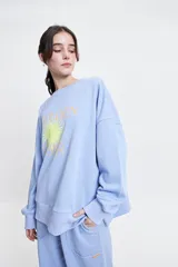 Buzo de felpa color marrón con estampa frontal en rosa, cuello redondo y hombros caídos.