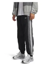 Pantalón deportivo tipo jogger Under Armour, color negro con franjas laterales en gris y blanco. Presenta cintura elástica con cordón interno, bolsillos laterales, bolsillo trasero con cierre y puños elásticos en los tobillos.