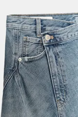 Falda midi de denim con diseño asimétrico en el bajo. Presenta tiro medio, trabillas para cinturón, cinco bolsillos clásicos y cierre frontal con cremallera y botón metálico.