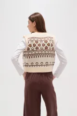 Chaleco tejido de punto con diseño jacquard de corazones y motivos geométricos en tonos verde y rosa. Presenta escote en V, cierre frontal con botones y terminaciones acanaladas en cuello, sisas y ruedo.
