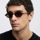 Lentes de sol con montura ovalada de color marrón chocolate y lentes polarizadas en tono marrón. Presentan un diseño de bordes finos y definidos con protección UV400.