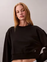 Buzo cropped de cuello redondo, manga larga con puños acanalados y dobladillo con punto canalé. Presenta un diseño corto y una pequeña insignia con el logotipo de Calvin Klein en el lateral.