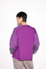Buzo violeta de jogging con friza, corte holgado y mangas balloon. Tiene un estampado bordado con lurex.