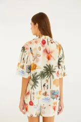 Camisa de lino y algodón color crudo con estampado de escenas de playa tropicales, de corte holgado, con cuello abierto y mangas cortas.