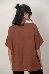 Blusa de lino color blanco, de corte amplio, con escote redondo, mangas cortas y detalle de guarda calada horizontal en la parte inferior.
