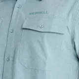 Camisa de manga corta Merrell, color verde claro, con cuello clásico, cierre frontal de botones y dos bolsillos frontales con solapa en el pecho. Presenta logo de la marca estampado en el lado izquierdo del pecho.