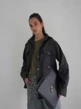 Camisa de lana color gris oscuro, de corte clásico con bolsillos frontales con solapa, cuello camisero y cierre frontal con botones.