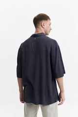 Camisa blanca de manga corta, corte oversize y cuello clásico.