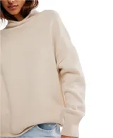 Buzo de tejido punto color beige claro, de calce oversized y cuello alto. Presenta mangas largas con puños anchos y dobladillos enrollados en ruedo y puños.