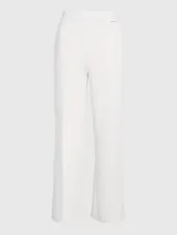 Pantalón blanco de pierna ancha confeccionado en tejido de punto técnico con poliéster reciclado y elastano. Presenta talle medio, pinzas delicadas en el centro de la pierna, bolsillos con ranura y barra de metal con logo de Calvin Klein debajo de la cintura.