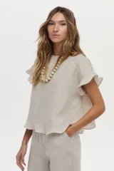 Blusa de lino color beige, de manga corta con volados, cuello redondo y espalda cruzada con volados.