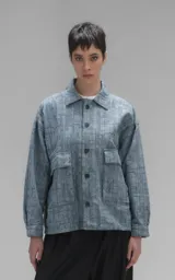 Campera de denim rígido con diseño de trama texturizada, corte oversize, cuello camisero, bolsillos frontales con solapa y cierre mediante botones.