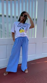 Pantalón de corte ancho y relajado, confeccionado en lino con diseño de rayas verticales. Presenta cintura elástica con cordón de ajuste y bolsillos laterales.