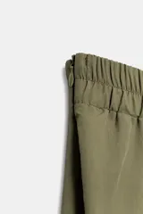 Falda midi de tiro alto en color verde militar, con diseño acampanado y cintura elástica. Presenta costuras verticales que definen su estructura y cierre lateral con cremallera oculta.