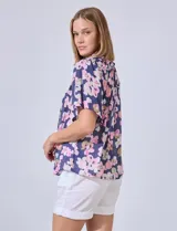 Blusa de gasa estampada con flores rosas y verdes sobre fondo azul marino. Escote bote con punto smock y mangas cortas amplias.