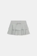 Minifalda gris melange de tiro medio, confeccionada en mezcla de algodón, con cintura elástica ajustable con cordones y diseño de doble volante en el bajo.