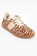 Zapatilla de cuero con textura de pelo y estampado animal print de puntos, con detalles en cuero liso color crema en los laterales y talón, y suela de goma color caramelo.