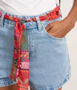 Short de jean azul con corte slim, cierre de botón y cremallera, bolsillos delanteros y traseros, y cinturón tipo pañuelo estampado multicolor incluido.