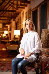 Camisa blanca de algodón con cuello mao, corte amplio, mangas largas abullonadas con puños abotonados y detalle de canesú con pliegues en el pecho.