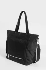 Cartera tipo shopper color beige de nylon, con doble asa de hombro y bolsillos frontales con cierres metálicos y tiradores de cordón negro.