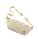 Riñonera Rip Curl modelo Everyday, color beige, con cierre frontal de cremallera, correa ajustable y detalle de logo metálico circular en la parte inferior.