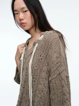 Buzo de tejido de punto con diseño de ochos, capucha integrada con cordones ajustables en contraste, manga larga y corte holgado.