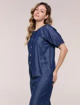 Blusa de calce relajado de lyocell en tono azul denim, con cuello a la base y cierre frontal de botones metálicos. Tiene mangas cortas abullonadas con puños elásticos.