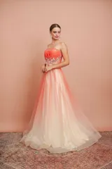 Vestido largo strapless de tul en degradé con tono coral y crema, con telas superpuestas y detalles bordados en el talle.